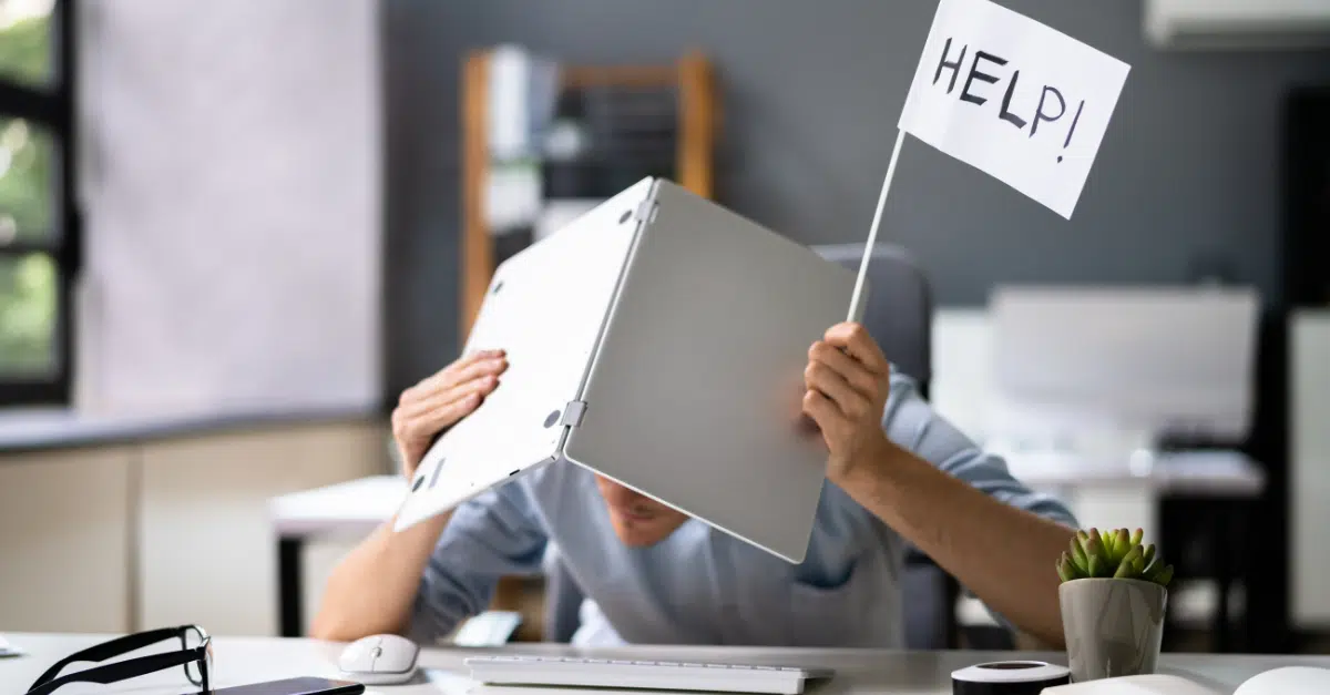man hiding face under laptop